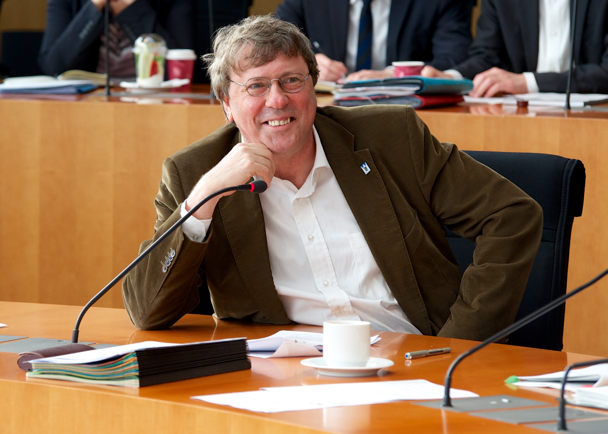 Uwe Schummer MdB sitzt an einem Tisch eines Ausschussraumes des Deutschen Bundestages.