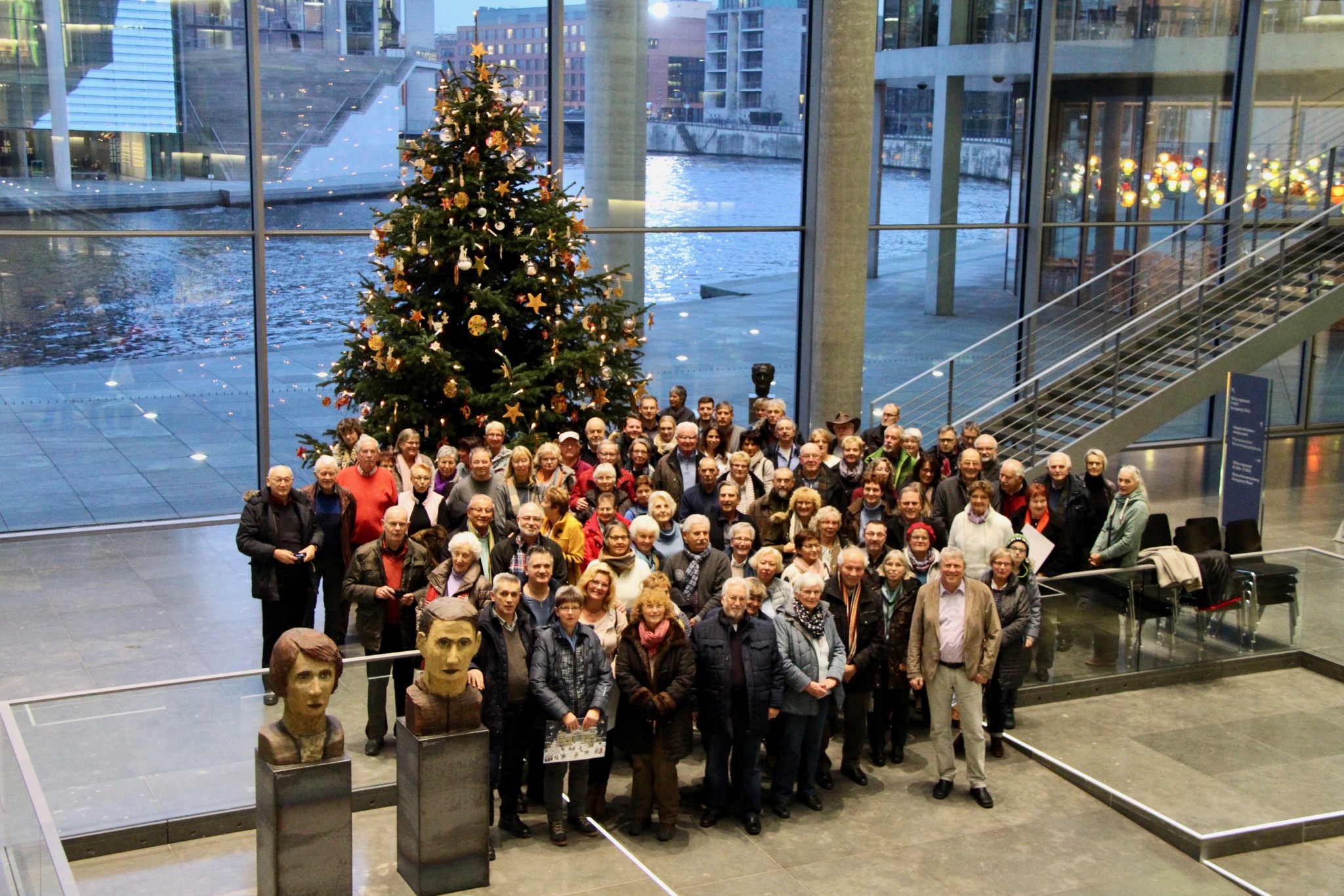 Uwe Schummer und Besucher vor dem Weihnachtsbaum im Paul-Löbe-Haus.